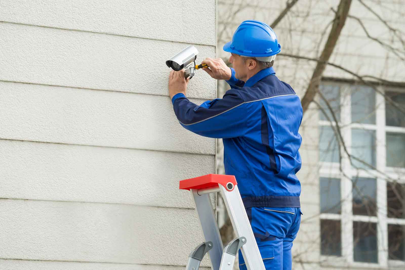 security camera technician on a ladder checking a security camera